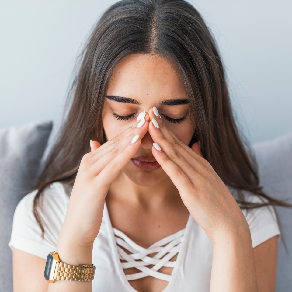 Sinus ache causing very paintful headache. Unhealthy woman in pain. Sharp strong sore. Sinus pain, sinus pressure, sinusitis. Sad woman holding her nose and head because sinus pain