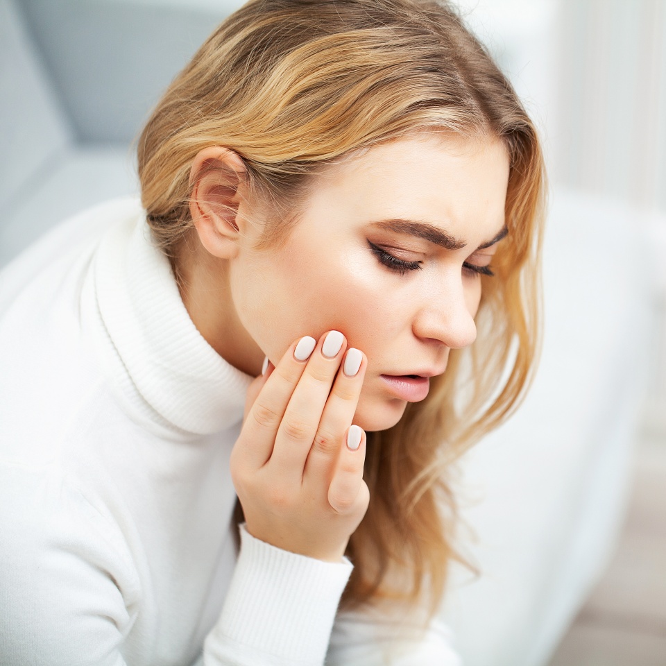 Pain. The problem of teeth. A woman feels pain in her tooth. A picture of a beautiful, sad girl suffering from severe pain in her teeth. An attractive woman feels painful toothache