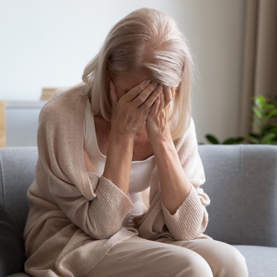 Depressed older woman covering face with hands, crying, feeling desperate. Unhappy mature grandmother experiencing grief, relative’s death, bad news. Stressed elder lady suffering from loneliness.