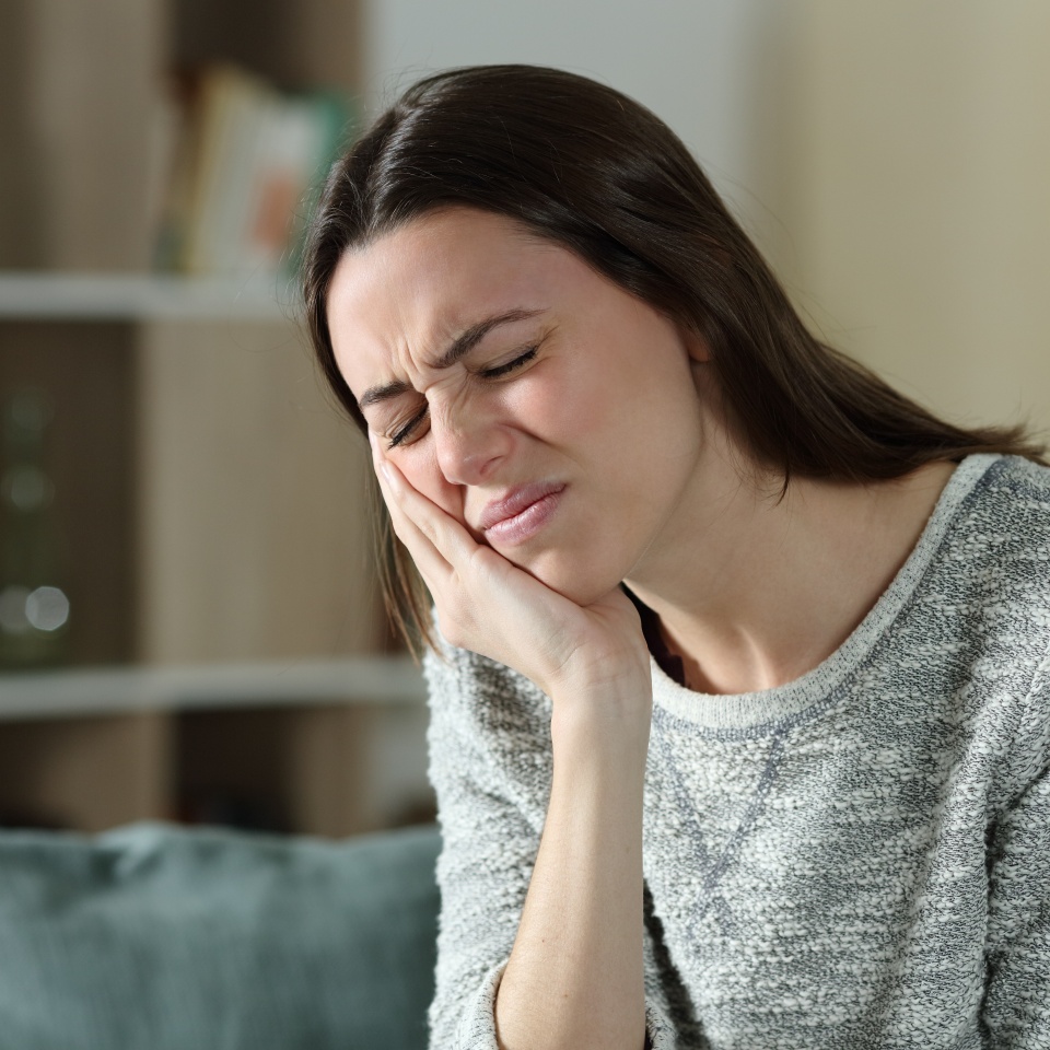 Stressed woman complaining suffering toothache sitting on a couch at home