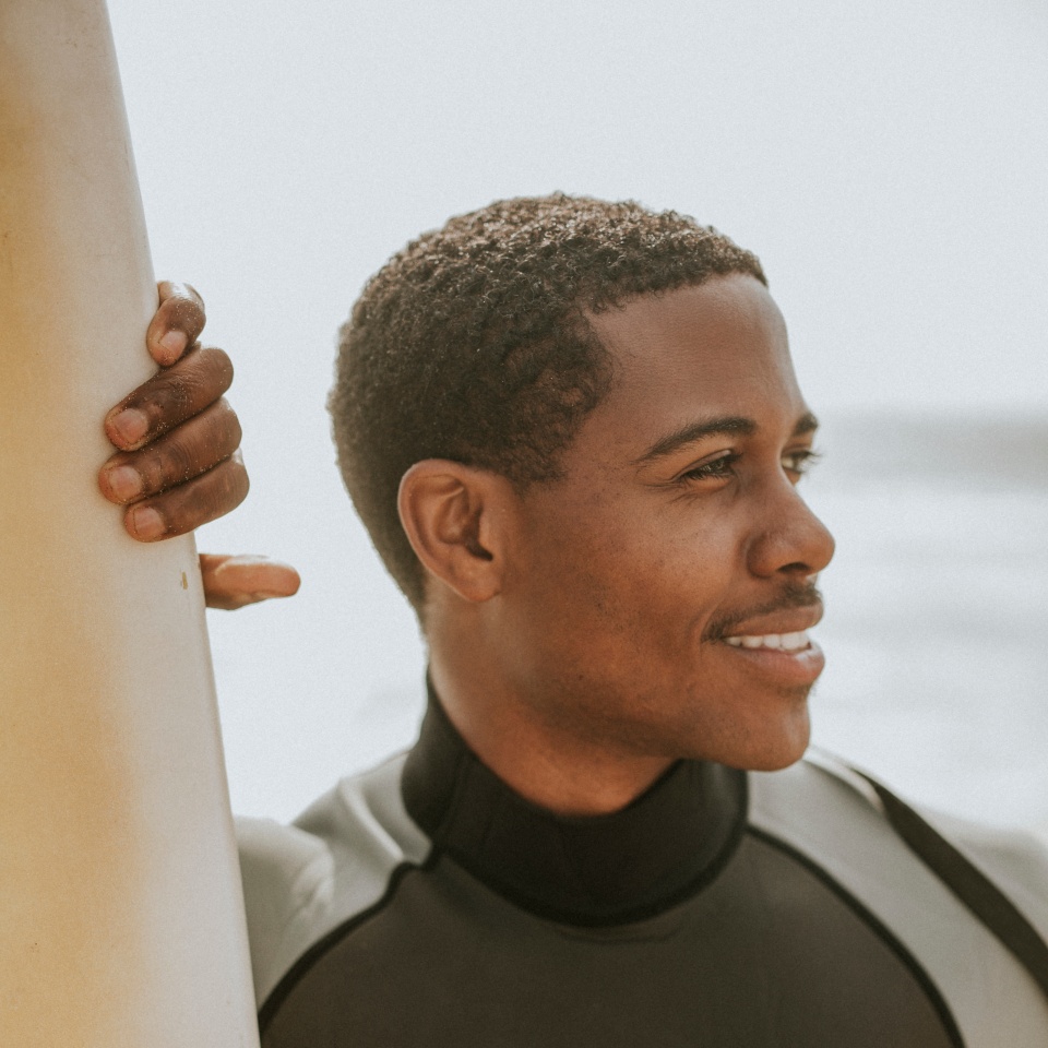 Black man standing by the surfboard