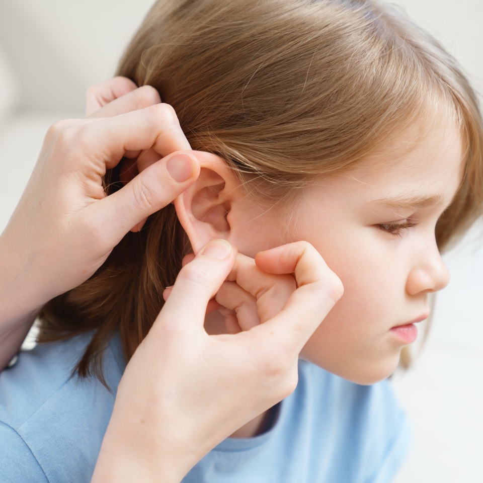 a little girl complains of pain in her ear and her mother examines it. children's diseases. corks in the ears and otitis. home remedies and medicines to treat children.