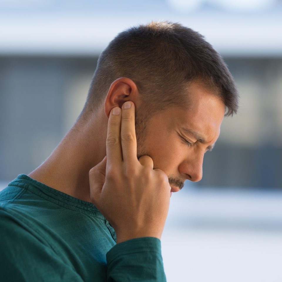 Man with tinnitus. Man touching his ear because of strong earache or ear pain. Otitis