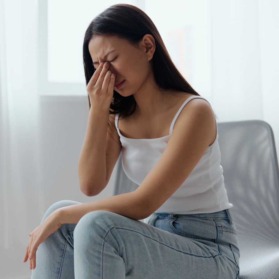Rhinitis Sinusitis Flu. Suffering tormented tanned beautiful young Asian woman hold hand on nose bridge posing isolated on white background. Injuries Poor health Illness concept. Cool offer