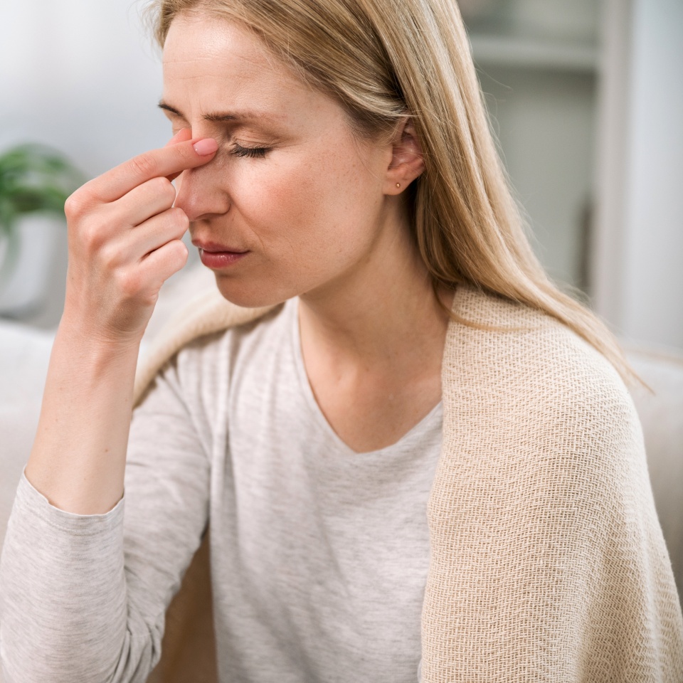 overworked woman with headache touching her nose bridge feeling tired and stress. sick young female with nasal discomfort suffering from sinusitis or respiratory infection