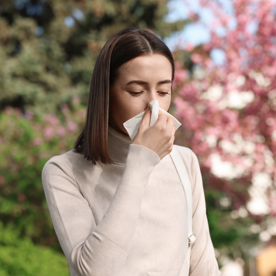 Woman with napkin suffering from seasonal allergy on spring day