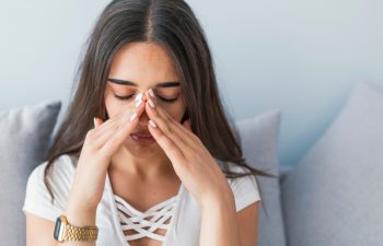 Sinus ache causing very paintful headache. Unhealthy woman in pain. Sharp strong sore. Sinus pain, sinus pressure, sinusitis. Sad woman holding her nose and head because sinus pain